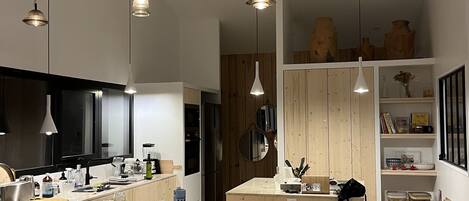 A modern kitchen with a central island, pendant lighting, and wooden cabinetry.