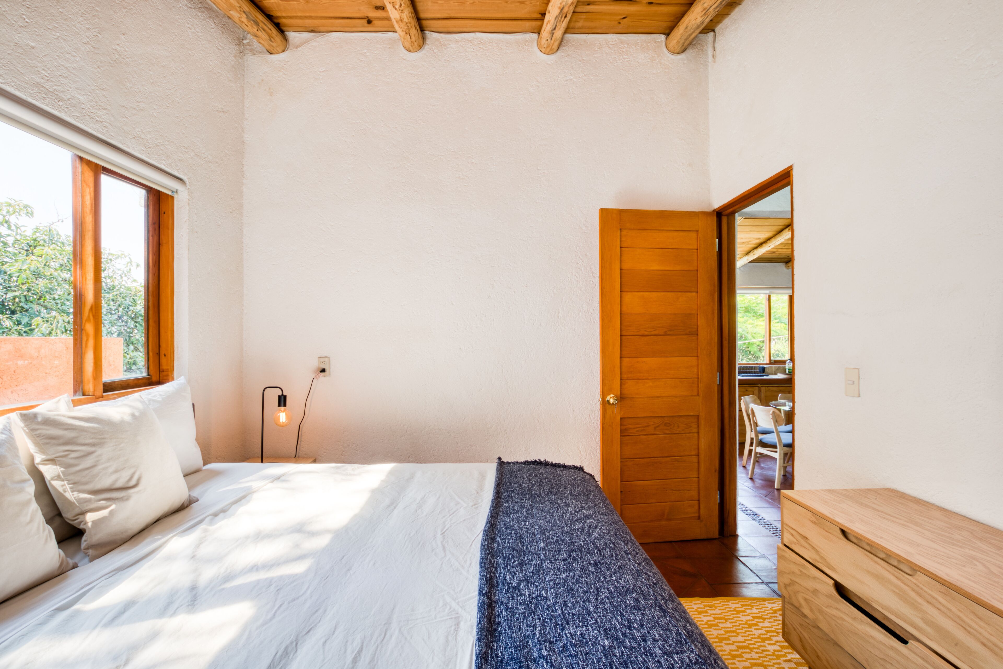 A bedroom with a bed, a wooden door, and a window.
