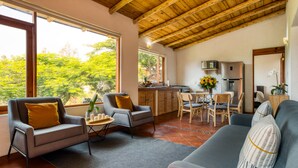 Un espacio habitable amplio con techo alto, una mesa de comedor y una cocina al fondo.