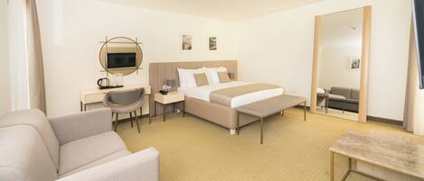 Una habitación de hotel con cama, escritorio con silla, sofá y un espejo grande.
