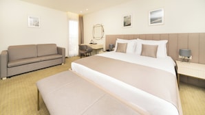 Une chambre d’hôtel avec un grand lit, un canapé, un bureau et un banc.