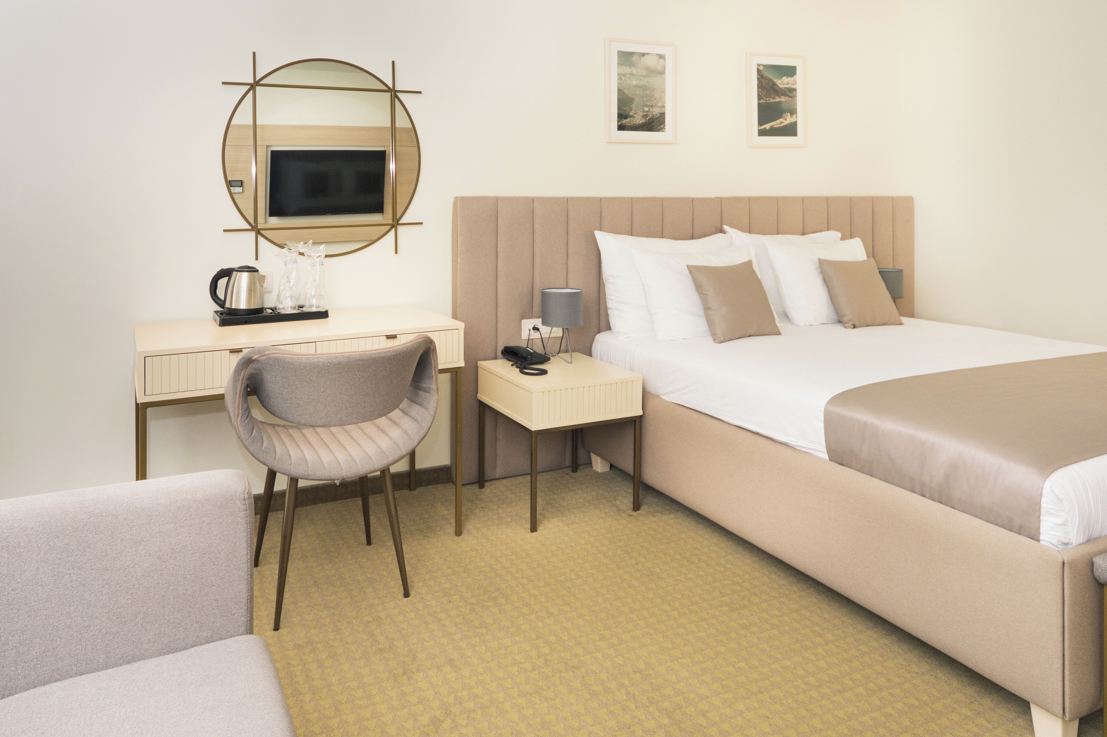 Habitación de hotel con cama, escritorio, silla, mesita de noche y espejo.