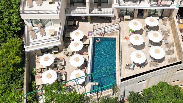 A multi-story hotel with balconies, outdoor seating, and a swimming pool. - Hotel Pima Budva (Budva)
