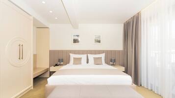 Una habitación de hotel moderna con una cama grande, mesitas de noche, un banco y un armario.