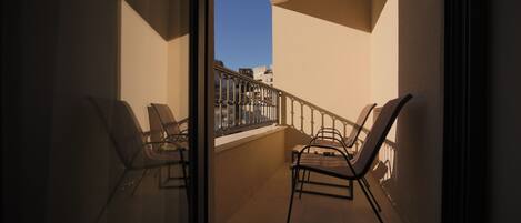 A balcony with two chairs and a table, a glass door, and a view of buildings.