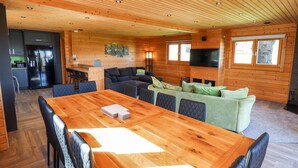A spacious living area with a large wooden dining table, comfortable seating, a kitchen area with modern appliances, and a television mounted on the wall. - Ilodge Ultra (Louth)