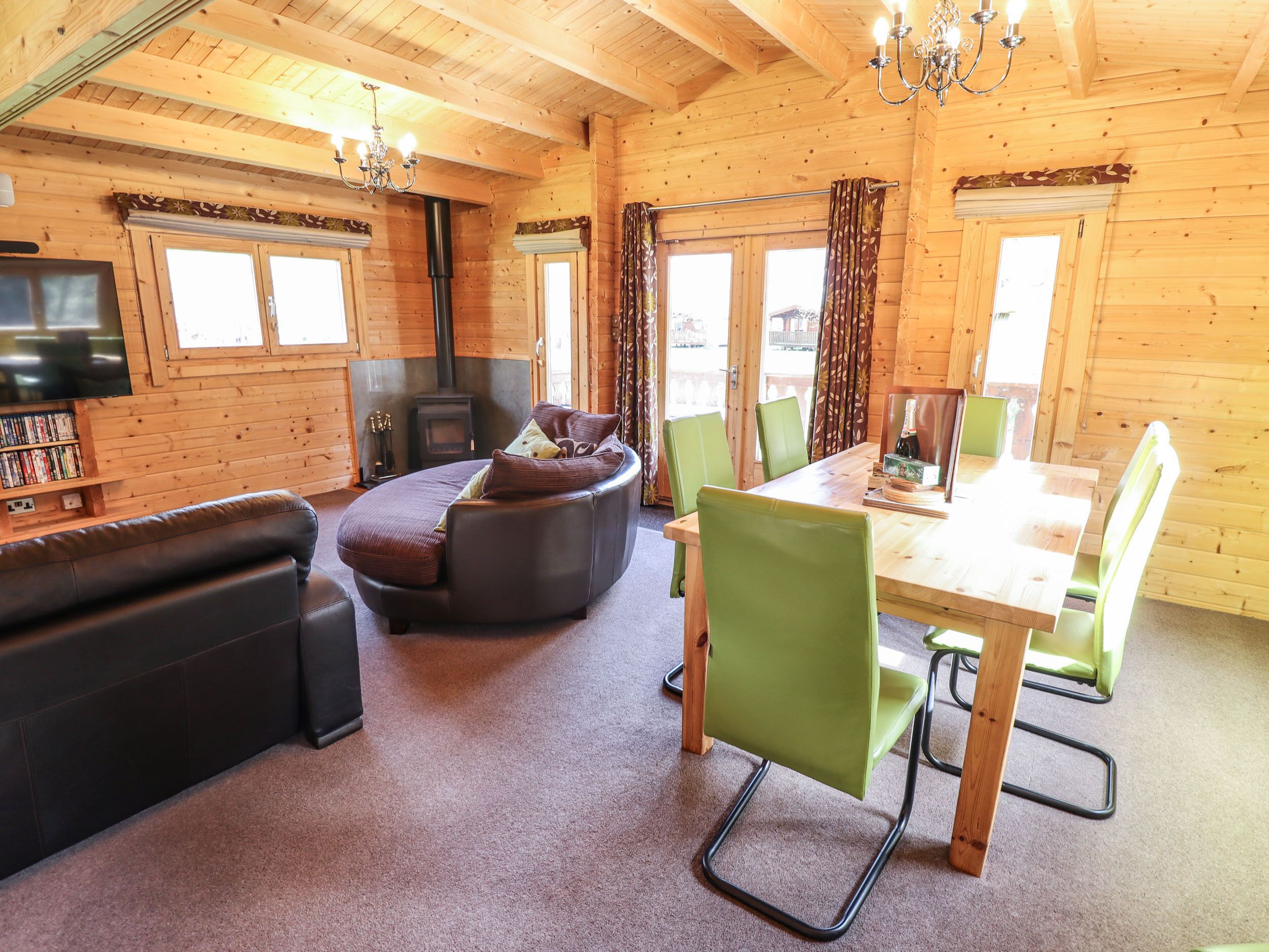 L’intérieur d’un chalet confortable, avec un canapé, une table à manger et des chaises, une cheminée et un téléviseur.