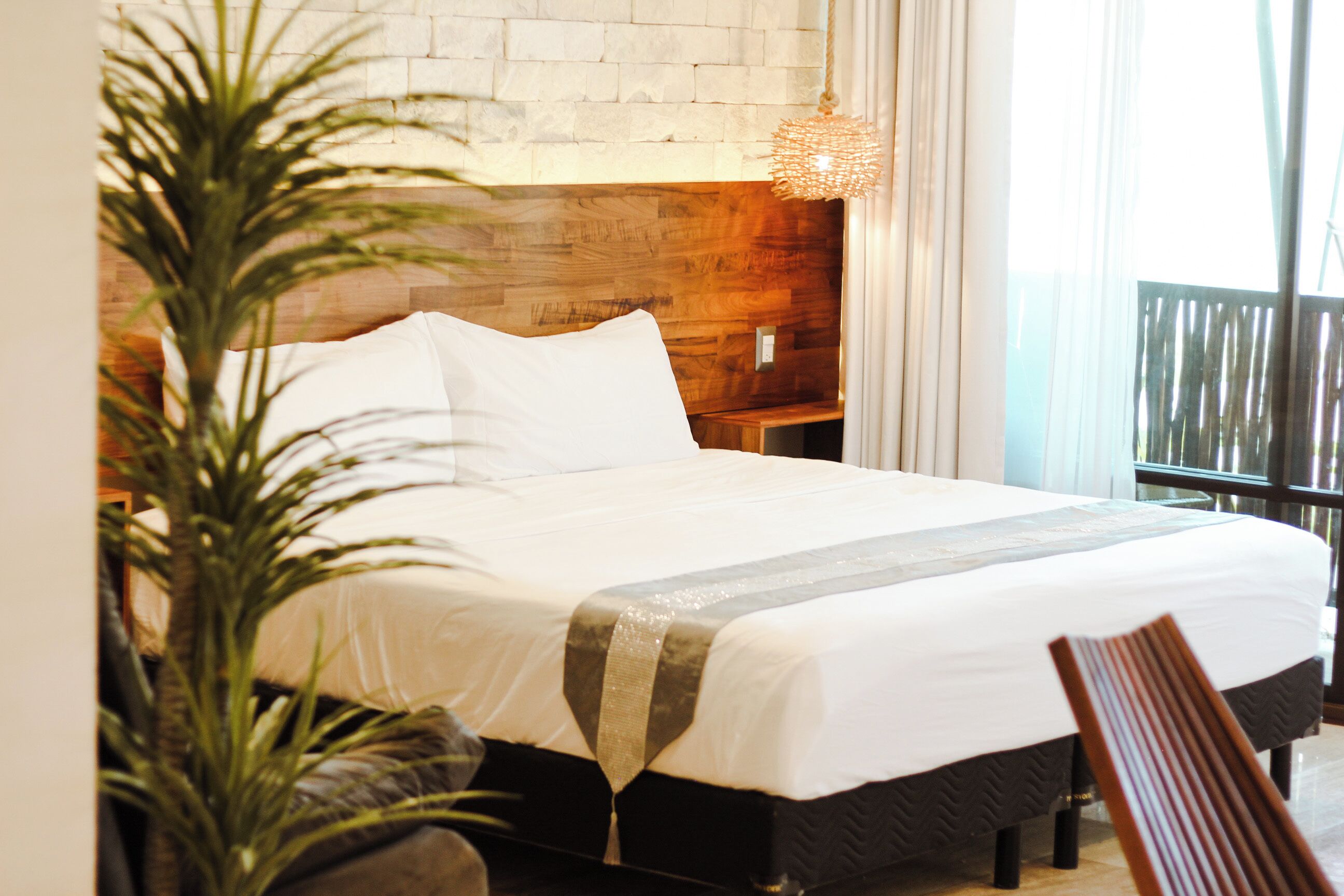 A neatly made bed with white linens, a wooden headboard, and a bedside table.