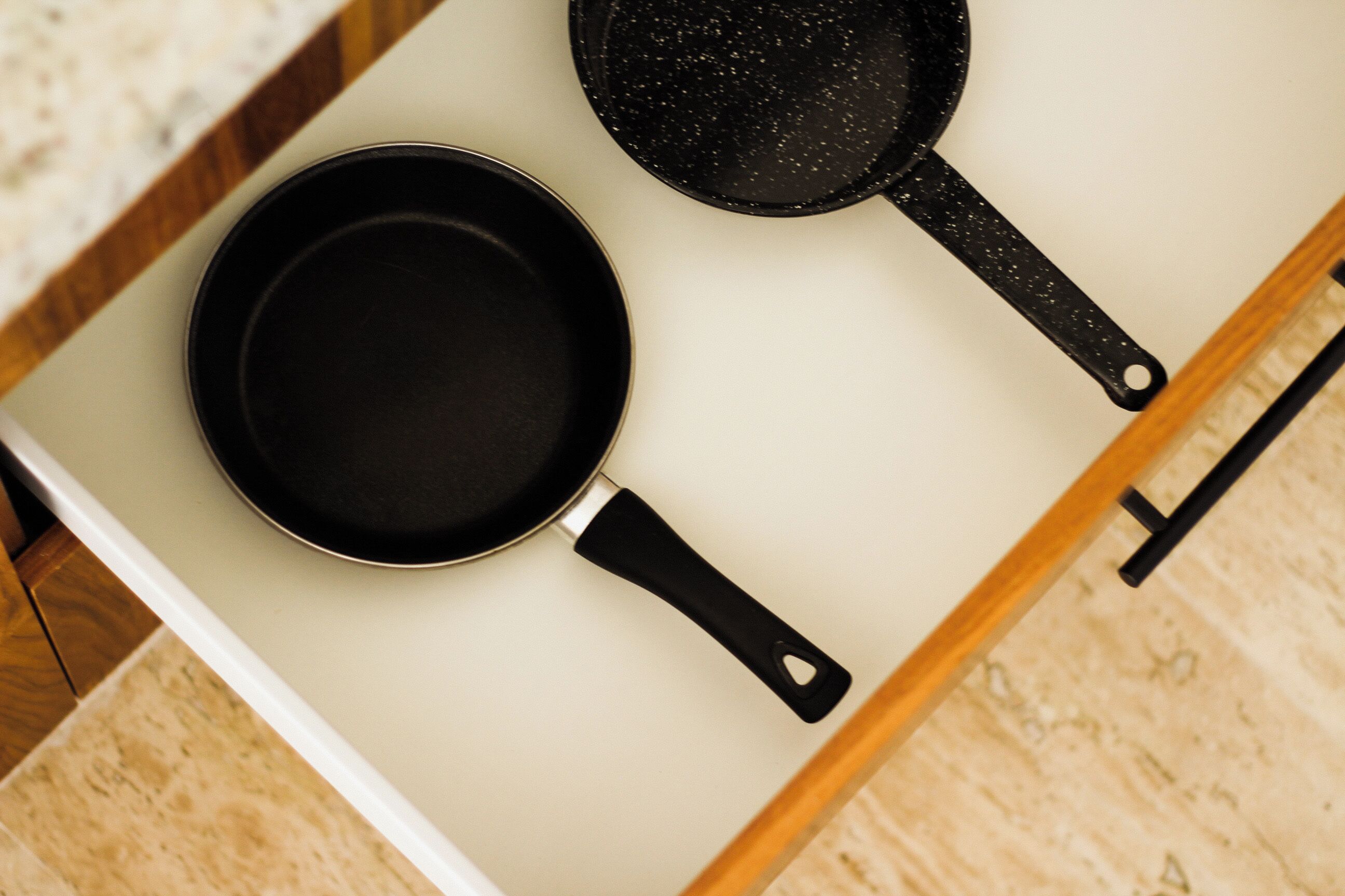 Un cajón de cocina con dos sartenes negras.