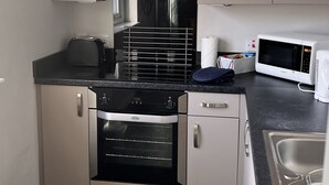 A modern kitchen with a built-in oven, microwave, and stove. - The Market Street Apartments - Ulverston (Ulverston)