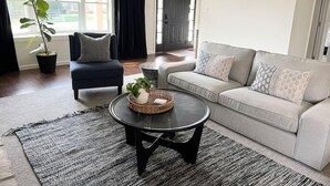 Ein Wohnzimmer mit einer Couch, einem Sessel, einem Couchtisch und einem Blumentopf.