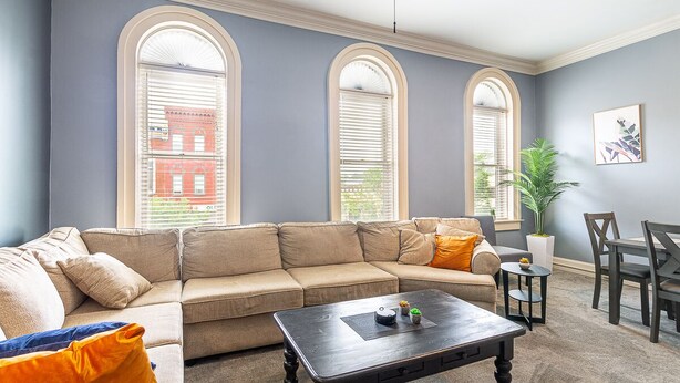 A living room with a beige sectional sofa, a dark wooden coffee table, and a dining area with a small table and chairs. - Lovely 2 bedroom downtown Three Rivers, sleeps 6 (Three Rivers)