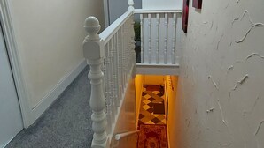 A staircase with a white railing, a red carpet, and a door at the top. - Ravensdale Villa- Ideal For Longer Stays in Kent (Gillingham)
