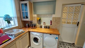 A compact kitchen with a washing machine, a toaster, and a sink. - Ravensdale Villa- Ideal For Longer Stays in Kent (Gillingham)