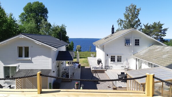 A coastal property with two white houses, a wooden deck, and a view of the sea. - Lakeview Loft, Private Retreat at Lake Skagern (Finnerödja)