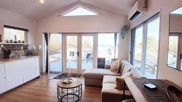 A spacious living area with a high ceiling, a dining table, a sofa, and a kitchen area with a countertop and cabinets. - Tree of Life Lakeview Loft Retreat (Finnerödja)