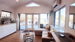 A spacious living area with a high ceiling, a dining table, a sofa, and a kitchen area with a countertop and cabinets. - Lakeview Loft, Private Retreat at Lake Skagern (Finnerödja)