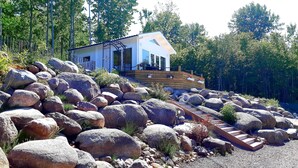 A modern house with a sloped roof, large windows, and a wooden deck. - Tree of Life Lakeview Loft Retreat (Finnerödja)