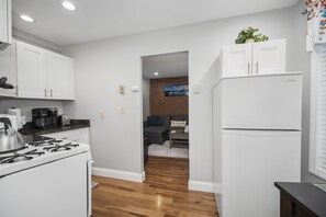 A modern kitchen with white cabinets, a gas stove, and a refrigerator.