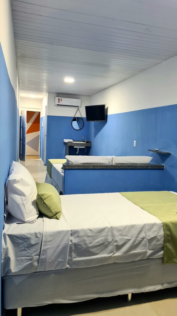 A room with two beds, a sink, and a television.