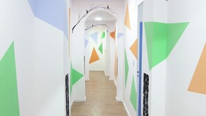 Un pasillo con paredes blancas, arte geométrico en la pared y suelo de madera.