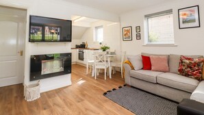Una sala moderna con chimenea, televisor, comedor y sofá.