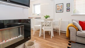 Una cocina moderna con armarios blancos, una estufa negra y un comedor con sillas y mesa blancos.