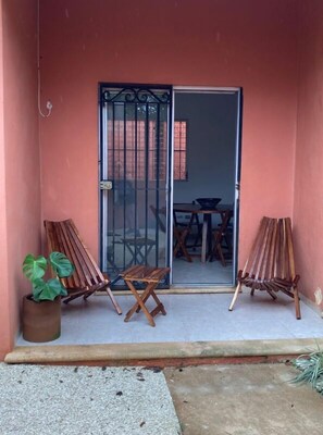 A small outdoor area with a sliding glass door leading to a dining space. There are two wooden chairs and a small table visible.