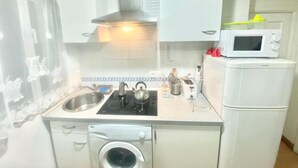 Eine kleine Küche mit Waschmaschine, Mikrowelle und Spüle.