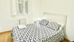 Ein Schlafzimmer mit Bett, Nachttisch, Lampe, einem Fenster mit Sternenmuster-Vorhängen und einer Heizung.