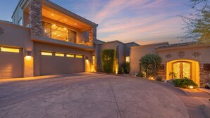 Een modern huis met twee verdiepingen, een stenen gevel, een ruime garage en een goed verlichte oprit.