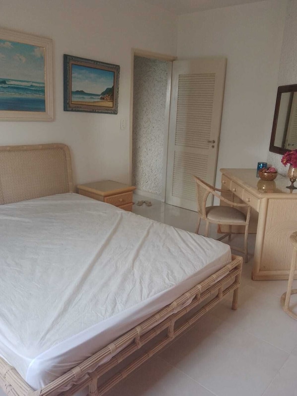 A bedroom with a bed, a desk, a chair, and a door.