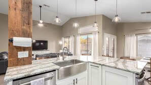 A modern kitchen with granite countertops, stainless steel appliances, and pendant lighting.