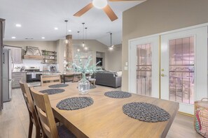 Une cuisine moderne avec un coin repas, une table en bois et des ventilateurs de plafond.