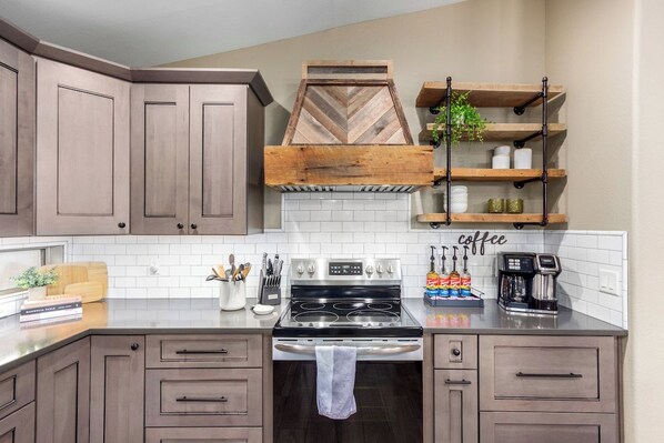 A kitchen with wooden cabinets, a stove, and a coffee station.