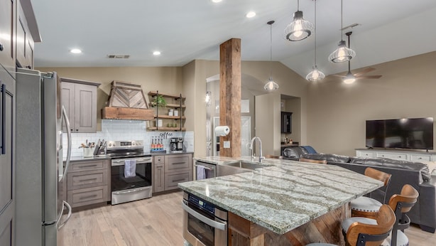 A modern kitchen with a large island, stainless steel appliances, and wooden accents.