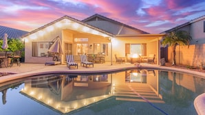 A modern house with a swimming pool, outdoor seating, and a patio area.
