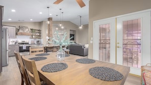 A modern kitchen with a wooden dining table, chairs, and a vase with decorative branches.