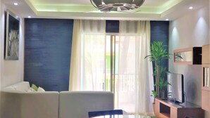 A modern living room with a glass dining table, a sofa, a TV, and a potted plant. - Huge Penthouse Near the Beach With Private Jacuzzi (Punta Cana)