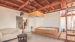 A modern bathroom with a wooden bathtub, a beige sofa, and a small wooden table. - Huge Penthouse Near the Beach With Private Jacuzzi (Punta Cana)