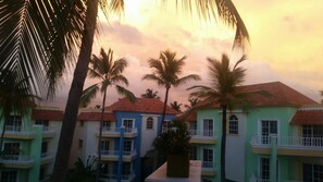 A resort with multi-story buildings, palm trees, and a sunset sky. - Huge Penthouse Near the Beach With Private Jacuzzi (Punta Cana)