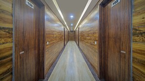 Un couloir aux murs lambrés et aux portes numérotées, donnant accès à des chambres individuelles.