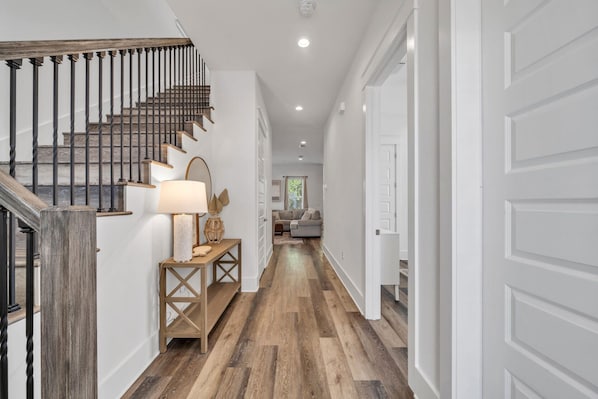 A staircase with wooden steps and black balusters, leading to a landing with a lamp and a decorative vase. - Beach getaway w/all you need - Location, Golf Cart, Walk to Beach & Pet-Friendly (Miramar Beach)