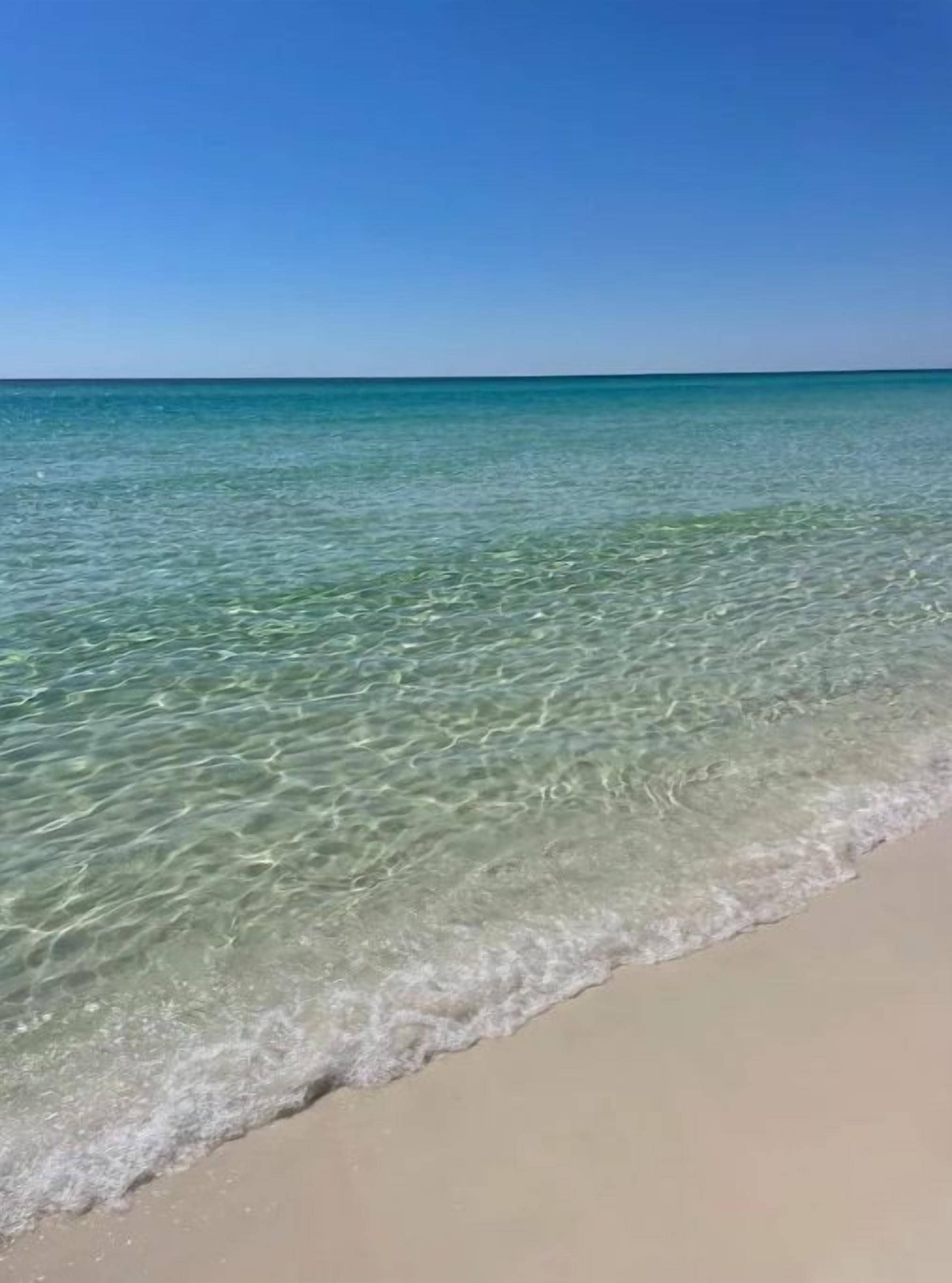 Uma praia com águas turquesa cristalinas e uma extensa faixa de areia.