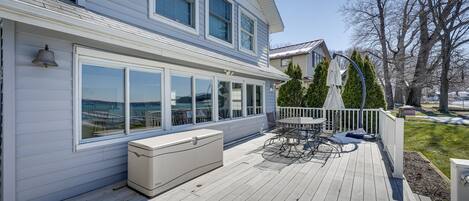 A two-story house with a deck, large windows, and a white exterior.