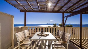 An outdoor patio with a table and chairs, a pergola overhead, and a view of the sea and mountains. - Apartment in Bol with Seaview, Terrace, Air condition, WIFI (5121-1) (Bol)
