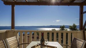 A table with a bottle and glasses on a tray, overlooking a scenic view of mountains and water. - Apartment in Bol with Seaview, Terrace, Air condition, WIFI (5121-2) (Bol)