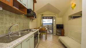 A compact kitchen with a built-in oven, a sink, and a dining area with a table and chairs. - Apartment in Bol with Seaview, Terrace, Air condition, WIFI (5121-2) (Bol)