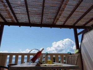 A covered outdoor seating area with a table, a bottle, and a glass. - Apartment in Bol with Seaview, Terrace, Air condition, WIFI (5121-5) (Bol)