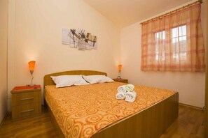 A hotel room with a bed, two bedside tables, a window with curtains, and wall art. - Apartment in Bol with Seaview, Terrace, Air condition, WIFI (5121-5) (Bol)